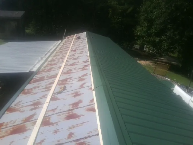 Old rusted panels beside newly installed green metal roofing — Wind Damage Roof Repair by Roofing Brothers in Keithville