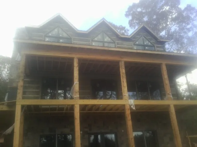 Dormers and porch framing on a large log home under construction — Roof Coating work by our crew in Keithville