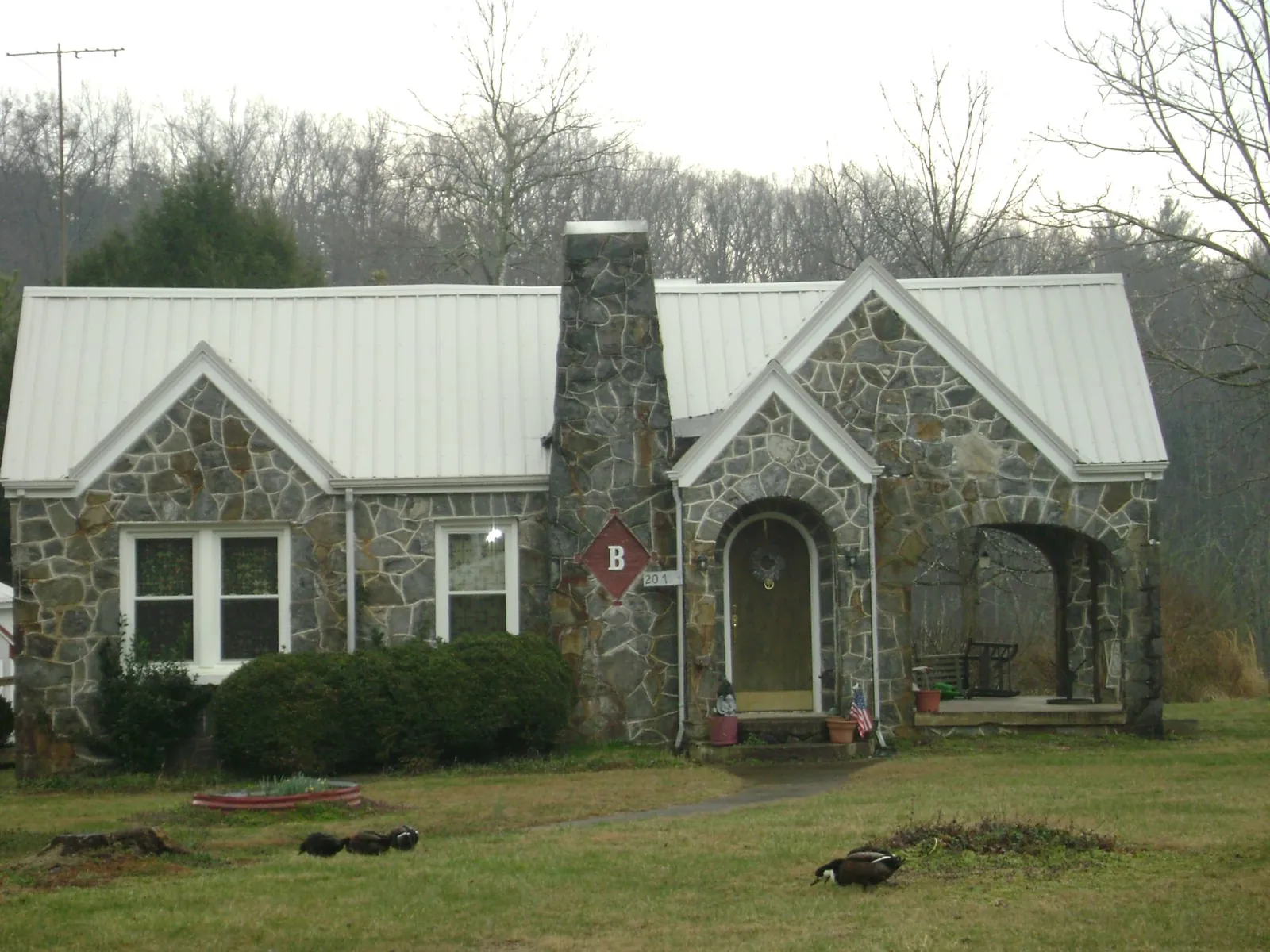 White metal roof on a stone cottage with steep gables in Keithville