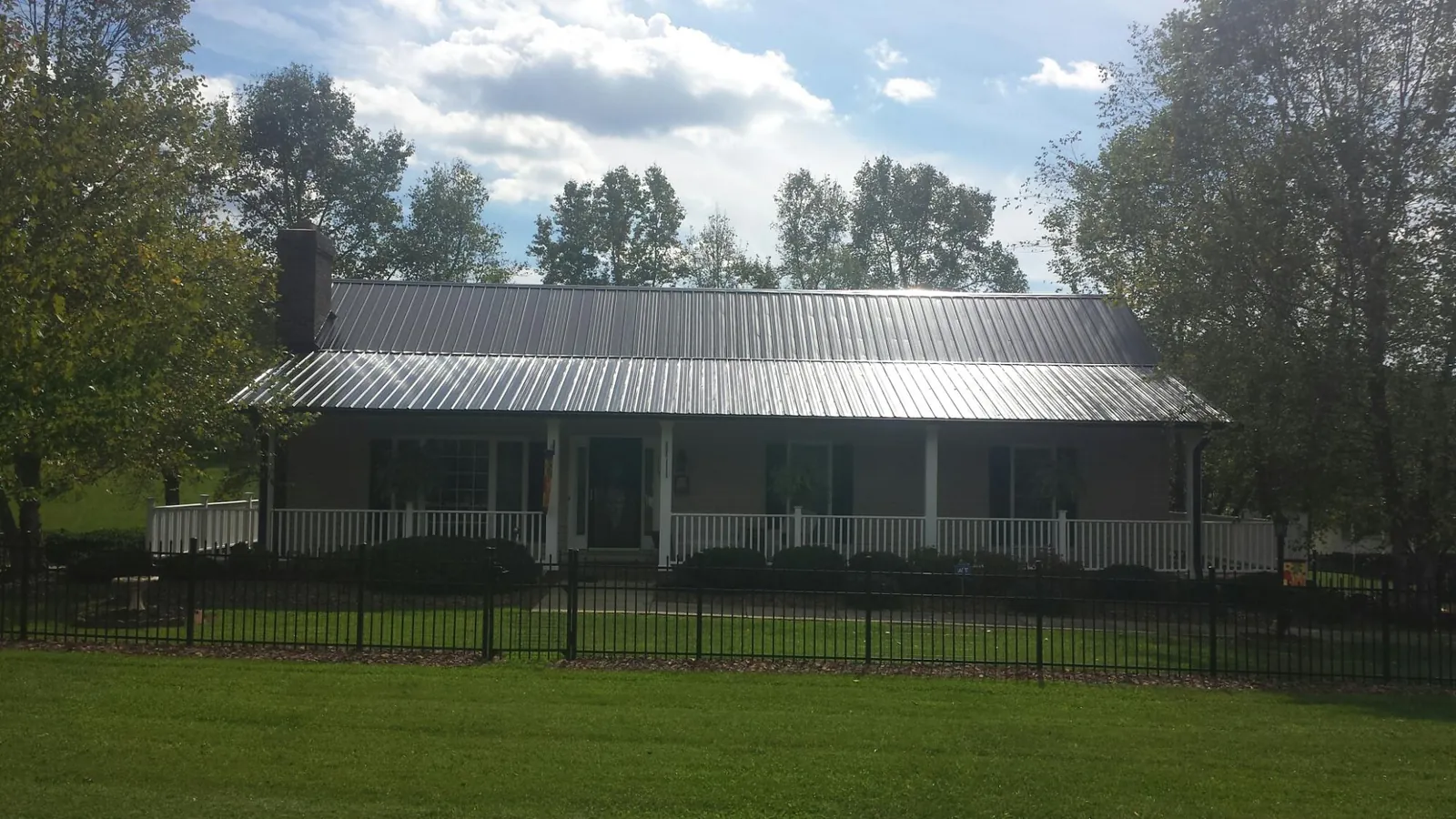Gray metal roof on a brick ranch with a full width front porch — Gutter Guard Installation work by our crew in Keithville