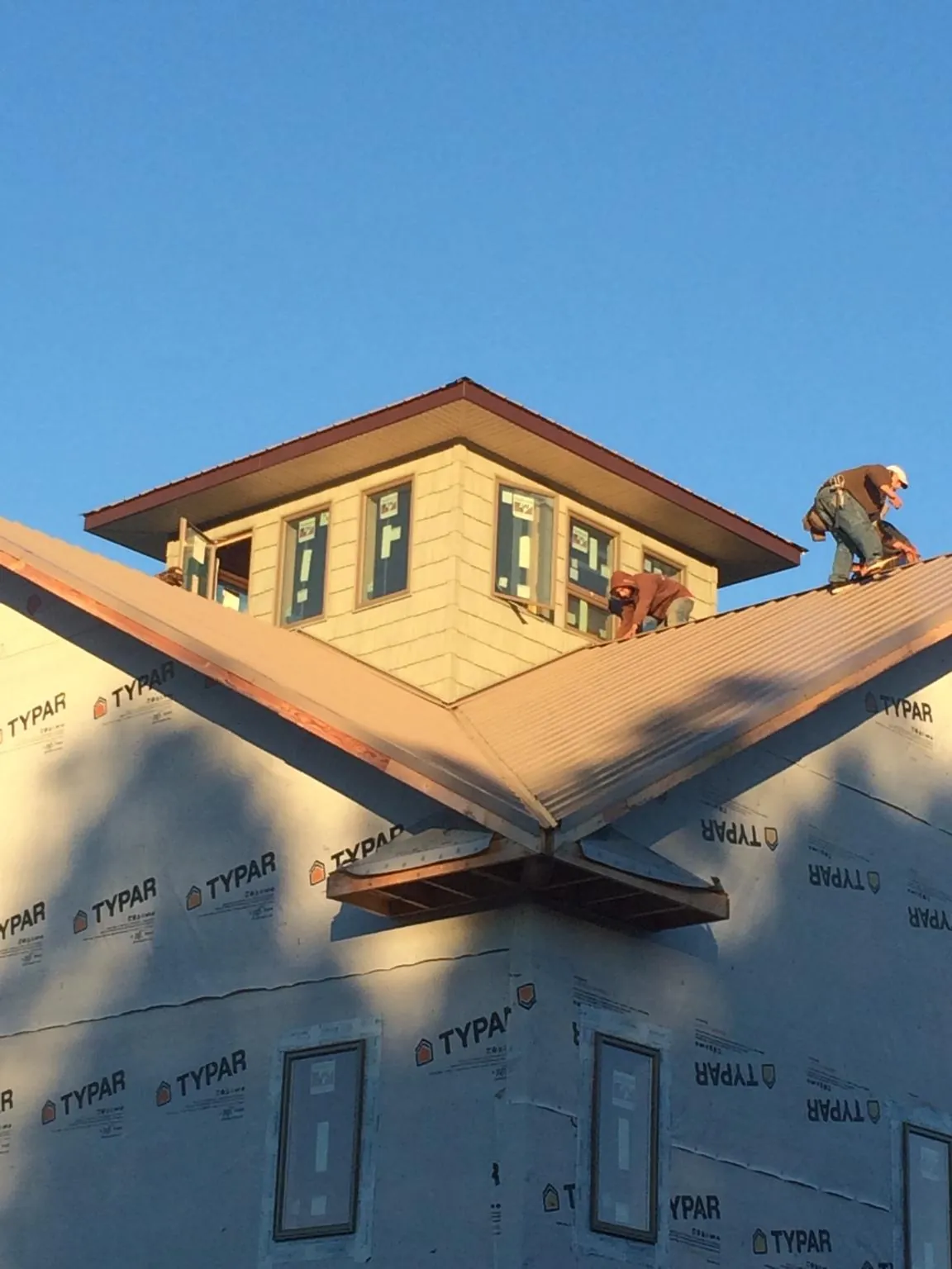 Roofers working around a rooftop cupola on a new metal roof at sunset — Roof Waterproofing in Keithville by Roofing Brothers